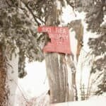 Snow-covered ski area boundary sign in Brighton, Utah, amidst winter landscape.